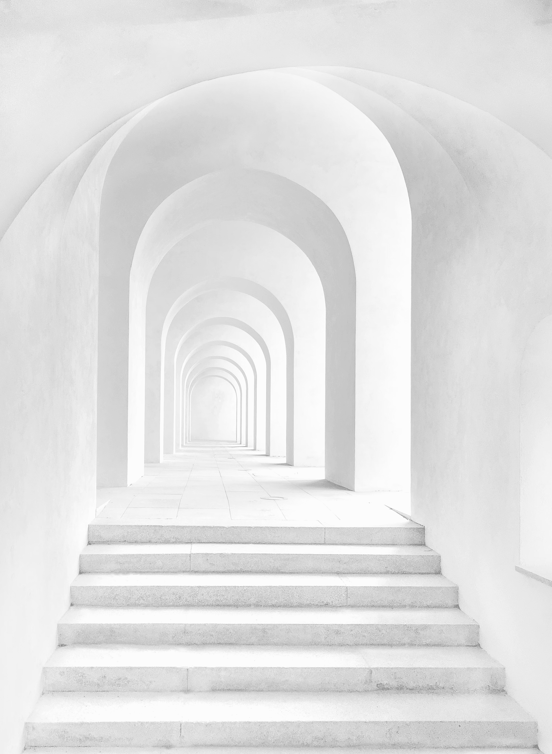 An image of a marble pathway starting with stairs, under some archways